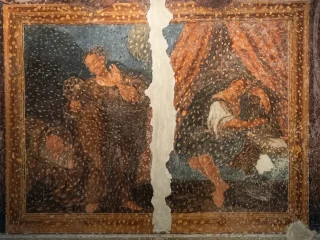 Affresco seicentesco diviso verticalmente da una larga lacuna centrale. A sinistra si vede una figura vestita con abiti scuri all’interno di una cornice decorata; a destra un’altra figura è seduta o reclinata sotto un tendaggio decorato. La superficie dell’opera presenta diffuse picchiettature realizzate per ridipingere la superficie.
