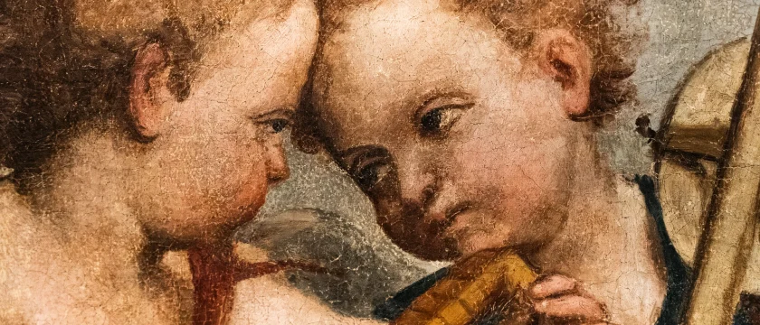 Dettaglio ravvicinato della pala di San Gottardo del Pordenone che raffigura due putti con capelli ricci, testa contro testa. Una delle figure tiene tra le mani un piccolo strumento musicale a fiato. La superficie pittorica presenta una trama visibile.