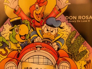 Un'illustrazione a colori tratta dalla copertina di un fumetto di Don Rosa che raffigura i Tre Caballeros. Paperino, con un'espressione determinata, è alla guida di un'auto rossa vintage, affiancato da José Carioca che tiene un ombrello e Panchito Pistoles che esulta sullo sfondo.