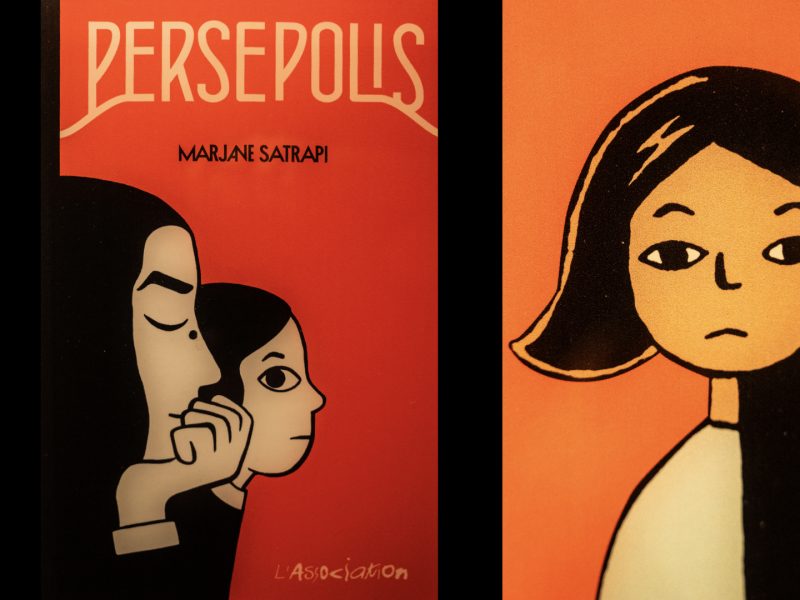 Un'inquadratura ravvicinata e leggermente alta mostra la copertina di una graphic novel del 2007 intitolata "PERSEPOLIS" di Marjane Satrapi. La copertina, a forma di rettangolo verticale e di colore rosso brillante, presenta l'illustrazione a linea nera di due figure di profilo a sinistra, una più vecchia e una più giovane, sovrapposte e rivolte a destra. Entrambe le figure hanno capelli neri e sono rese con un semplice contorno a linea nera. La figura più vecchia a sinistra è più grande, con un braccio appoggiato sul mento e la mano con un anello. La figura più giovane a destra è più piccola e mostra solo il viso e il busto. Il titolo "PERSEPOLIS" è scritto in grandi lettere capitali bianche in alto, sopra la scritta "MARJANE SATRAPI" in caratteri più piccoli. In basso, la scritta "L'Association" in bianco è visibile. A destra, il resto della copertina mostra l'illustrazione a linea nera di una giovane donna con capelli neri e un'espressione seria, che guarda dritto.