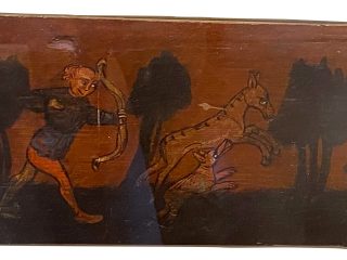 Pannello ligneo dipinto raffigurante una scena di caccia: una figura con arco affronta un animale tra alberi stilizzati su fondo marrone.