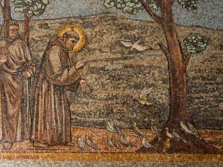 Mosaico murale con due figure religiose in abiti monastici accanto a un albero, con uccelli raffigurati a terra e in volo su uno sfondo naturale.