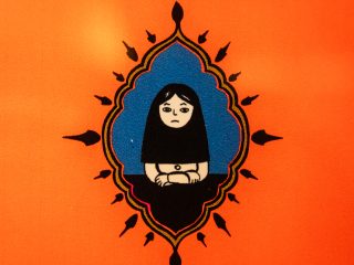 di una graphic novel del 2007 intitolata "PERSEPOLIS" di Marjane Satrapi. L'illustrazione stilizzata su un vivace sfondo arancione. Al centro, racchiusa in una cornice a forma di mandorla con un bordo blu e decorazioni a punta nere e oro, c'è una giovane donna con lunghi capelli neri e un'espressione malinconica. Indossa un semplice abito nero e tiene le mani incrociate davanti a sé. Lo stile è semplice e iconico, con colori piatti e contorni netti.